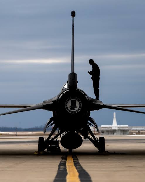 An Air Force mechanic walking in front of a fighter jet